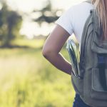 Hiking woman with backpack walking on a gravel road